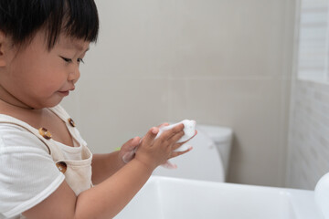 little kid hands wash with soap bubbles and rinse with clean water to prevent and stop the spread...