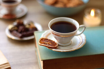 Books, reading glasses, e-reader, plate of chocolate pralines, bowl of cookies, cups of tea and lit...