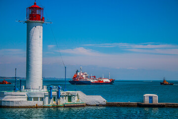 Ships sail out of the port area next to the lighthouse