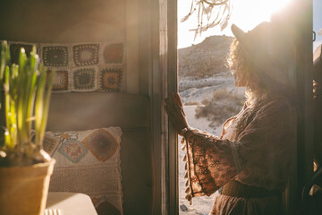 One dreamer travel woman admiring sunset light and landscape standing on the door of her tiny motorhome house. Wanderlust and female traveling solo. People enjoying freedom and vanlife lifestyle