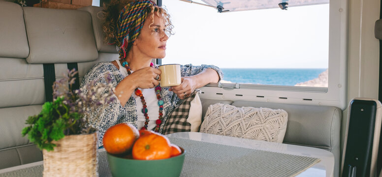 Happy oy woman tourist smiling and drinking view from inside her camper van. Vacation on renting vehicle motorhome concept lifestyle. Travel and summer happiness female people relaxing