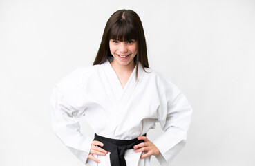 Little caucasian girl over isolated white background doing karate posing with arms at hip and...