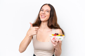 Young caucasian woman holding a bowl of fruit isolated on white background with thumbs up because something good has happened