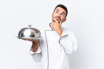 Young chef with tray isolated on white background having doubts