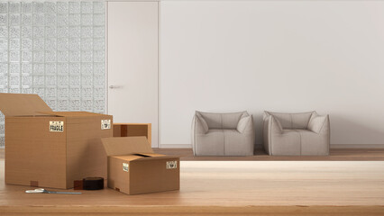 Wooden table, desk or shelf with stack of cardboard boxes over blurred view of sitting waiting room with glass brick wall, interior design, moving house concept with copy space