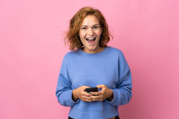 Young Georgian woman isolated on pink background surprised and sending a message