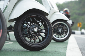 Close-up of wheels of a scooter motorcycle parked on a beautiful road in the daytime.