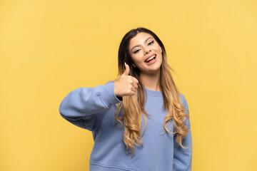 Young Russian girl isolated on yellow background with thumbs up because something good has happened