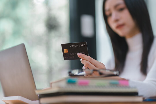 Close-up image of a woman making an online purchase on a computer using a mockup credit card. Selective focus