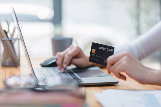 Close-up image of a woman making an online purchase on a computer using a mockup credit card. Selective focus
