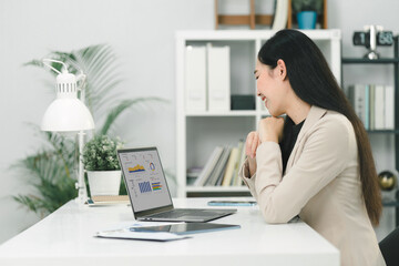 A businesswoman or accountant using laptop to analyze financial investments and business and marketing growth on a data graph. The concepts of accounting, economics, and commercial analysis.