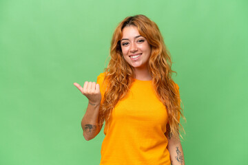 Young caucasian woman isolated on green screen chroma key background pointing to the side to present a product