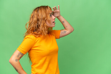 Young caucasian woman isolated on green screen chroma key background with surprise expression while...