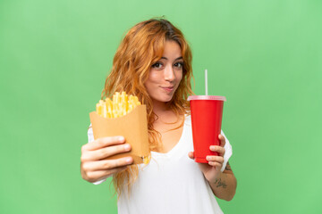 Young caucasian woman holding fried chips and soda isolated on green screen chroma key background  background