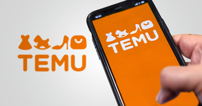 Hand holding a phone with Temu logo displayed on the screen