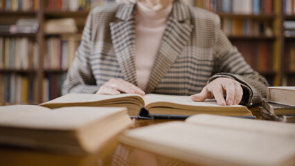 Close-up of mature woman reading a book, professor doing research in the library
