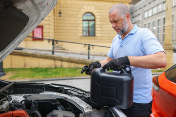 Fototapeta na wymiar The mechanic is pouring oil into the engine. Pouring fresh oil to car engine, oil change to auto. 