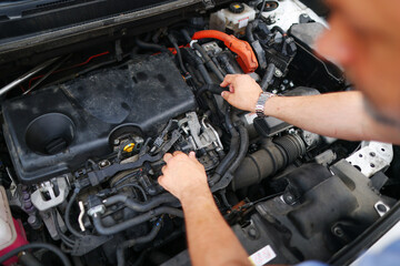 Obraz na płótnie Canvas male mechanics hands check electrical wiring vehicle system in a car service