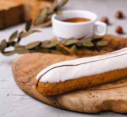 Glazed eclair dessert with coffee on wood
