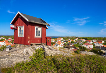 Red swedish wooden cottage on the top of the hill and a view at the cityscape of the island Vrango in Sweden, near the Gothenburg
