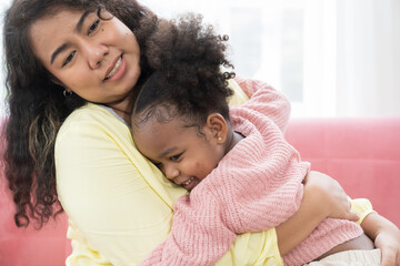 Asian mother and daughter embrace together at home. Happy African American little girl kid hugging with mom. Happy family spending time together