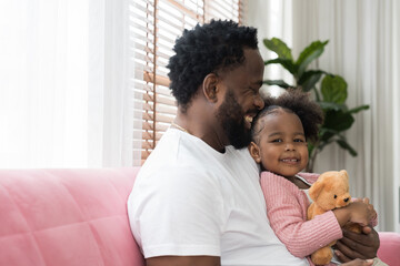 Father and daughter playing together at home. Happy African American little girl kid playing with...