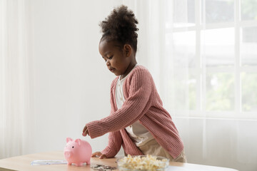 Girl kid putting money into the piggybank. African American girl kid inserting a coin in a piggy...