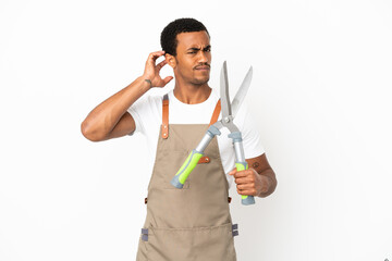 African American gardener man holding pruning shears over isolated white background having doubts