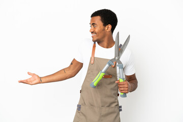 African American gardener man holding pruning shears over isolated white background with surprise expression while looking side