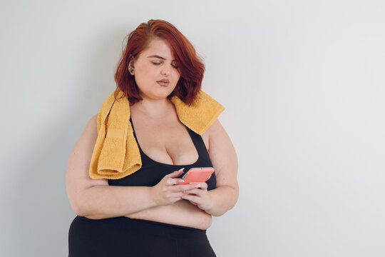 Young Sporty Plus Size Woman Using Phone On White Background, Copy Space