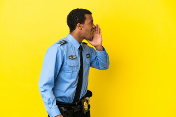 African American police man over isolated yellow background shouting with mouth wide open to the...