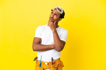 African American electrician man over isolated yellow wall and looking up