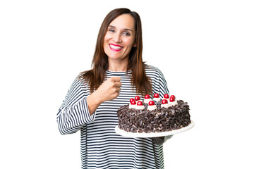 Middle age caucasian woman holding birthday cake over isolated chroma key background celebrating a victory