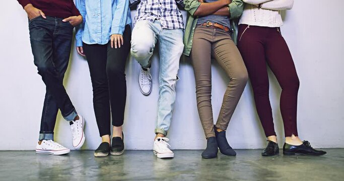 Group of people waiting at white wall, legs and youth relax in campus lobby together with men and women. Diversity, casual gen z candidates and feet of friends or university students standing in row.