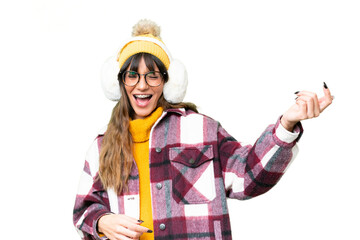 Young caucasian woman wearing winter muffs over isolated chroma key background making guitar gesture