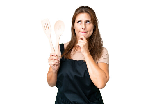 Middle age caucasian woman holding a rolling pin over isolated background having doubts and thinking