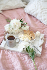 Fototapeta na wymiar Breakfast in bed. Coffee, croissant and cottage cheese. Next to the peonies