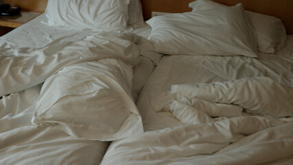 lit non fait avec des draps blancs. Lit vide non fait. Gros plan sur un drap de lit défait dans la chambre d'hôtel après une nuit de sommeil..