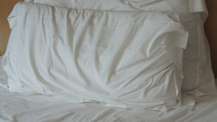 lit non fait avec des draps blancs. Lit vide non fait. Gros plan sur un drap de lit défait dans la...