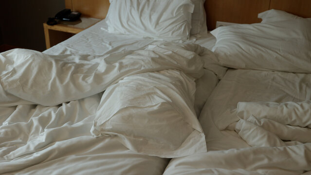 lit non fait avec des draps blancs. Lit vide non fait. Gros plan sur un drap de lit d&eacute;fait dans la chambre d'h&ocirc;tel apr&egrave;s une nuit de sommeil..