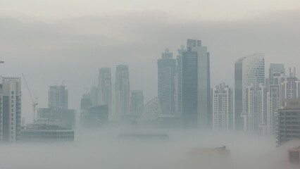 Dubai skyscrapers with morning fog in business bay district night to day timelapse.