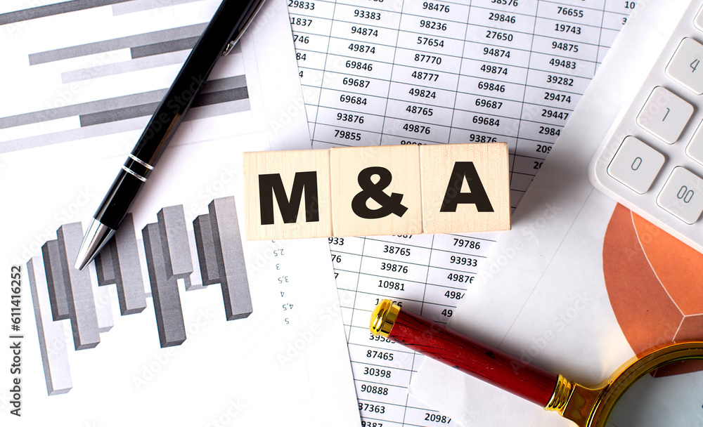 Poster M and A text on wooden block on graph background with pen and magnifier