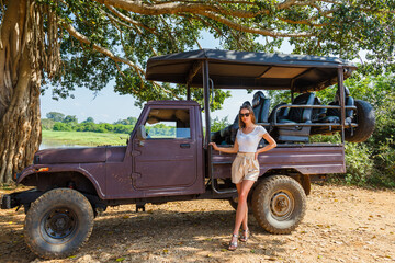 A woman in front of a car during a safari in Udawalawe National Park, Sri Lanka, with Ceylon elephants in the background © Alicja Wójcik