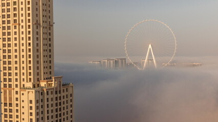 Bluewaters island with modern architecture and ferris wheel covered by morning fog aerial timelapse.