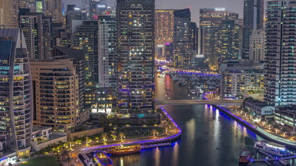 Fototapeta na wymiar Dubai Marina with several boat and yachts parked in harbor and skyscrapers around canal aerial day to night timelapse.