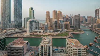 Panorama showing Dubai Marina with several boat and yachts parked in harbor and skyscrapers around canal aerial timelapse.