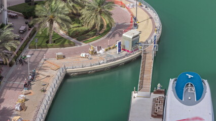 Waterfront promenade with palms in Dubai Marina aerial timelapse.