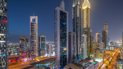 Fototapeta premium Aerial view of Dubai International Financial District with many skyscrapers day to night timelapse.