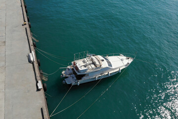 Aerial view of white moored boat or yacht at dock in sunny day, view from above. Copy space