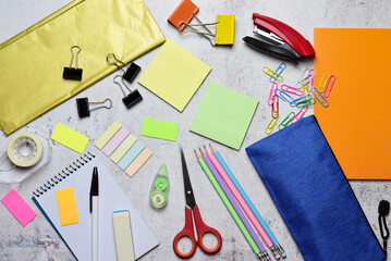 Assorted school supplies on light colored stone background, back to school. Zenit view.